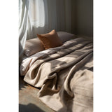 Cozy bed with beige blanket and pillow in a softly lit room